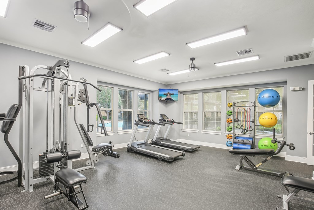 A spacious gym with a variety of equipment including treadmills, weights, and exercise balls.