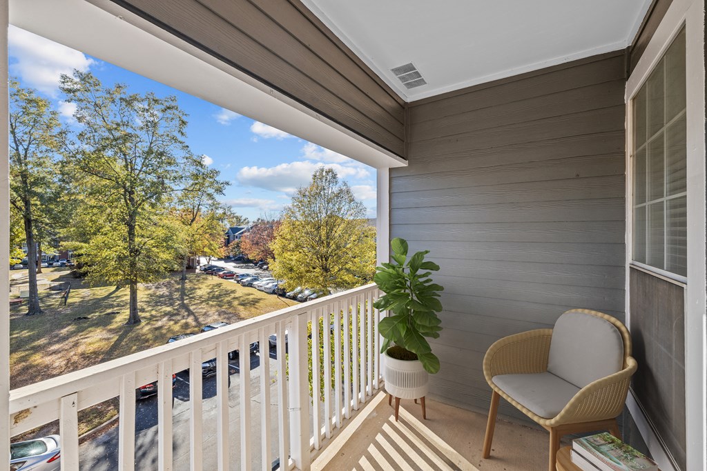 a balcony with a chair and a potted plant and a view of a park