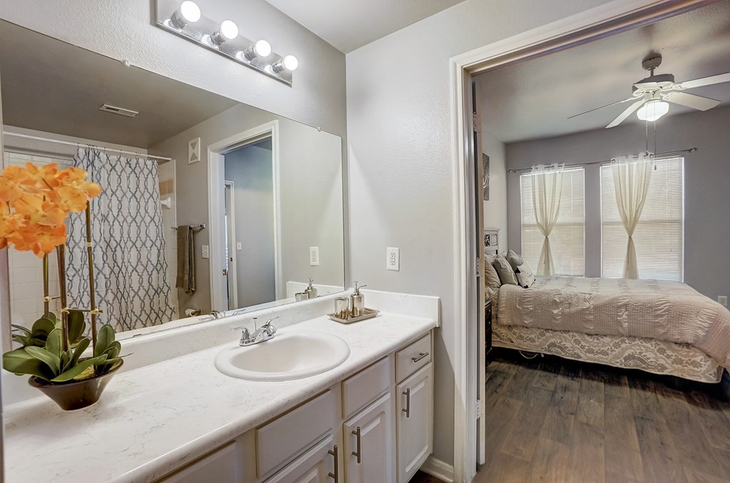 a bathroom with a mirror and a sink and a bedroom with a bed