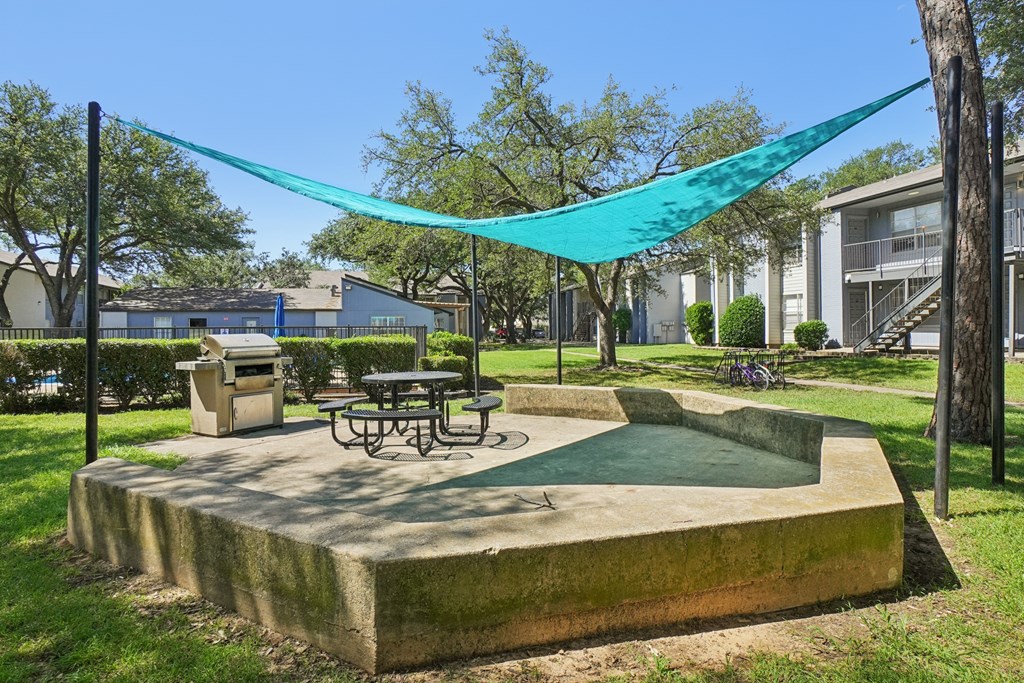 A concrete structure with a table and chairs under a blue tarp.