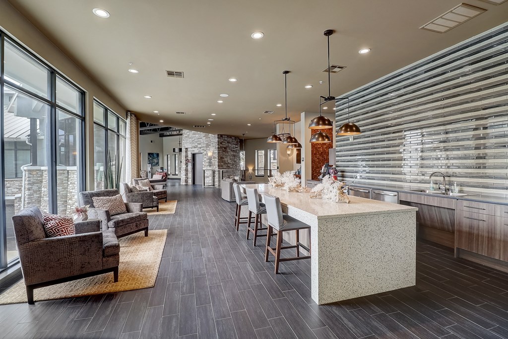 a large kitchen with a long counter with chairs and a table