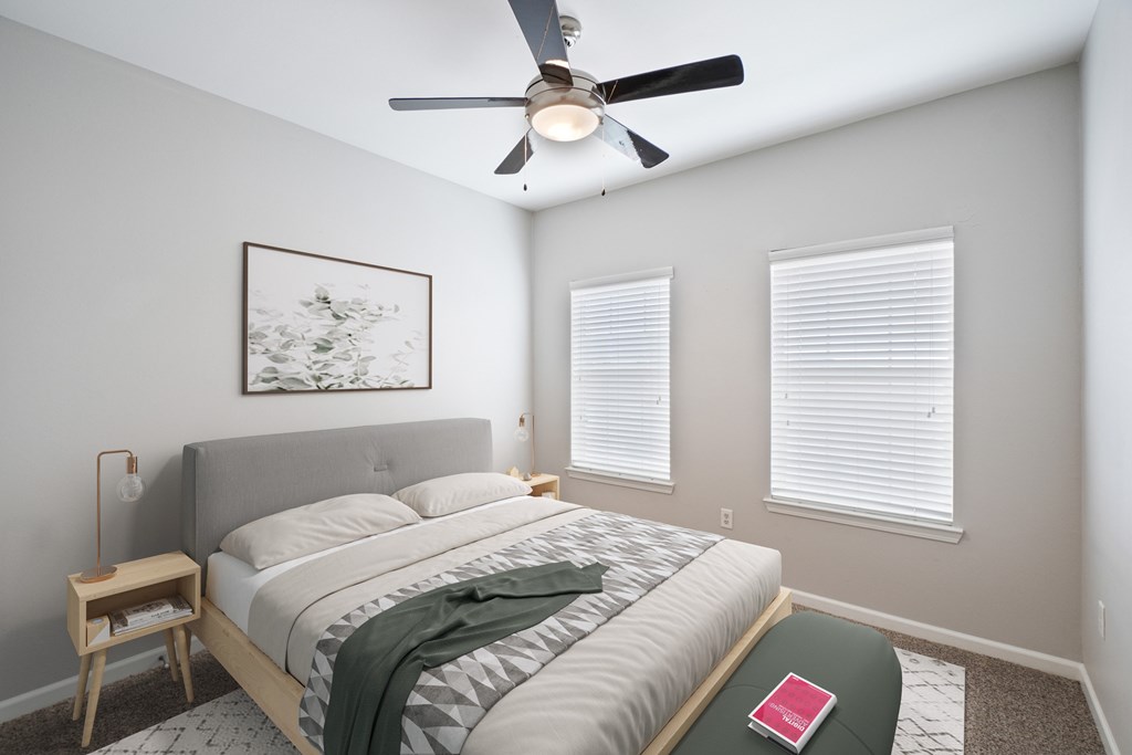 A bedroom with a bed, a ceiling fan, and a picture on the wall.