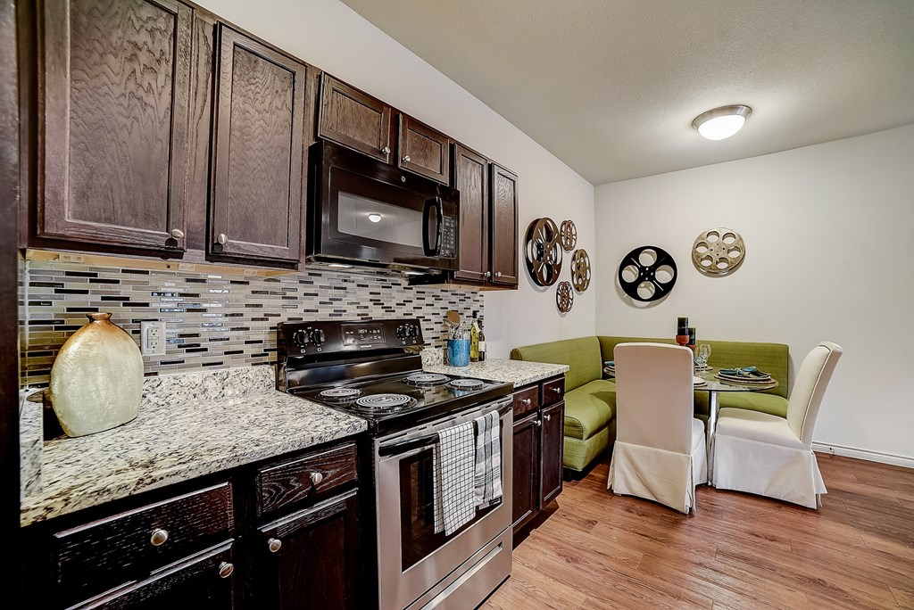 a kitchen with a stove top oven next to a table with a green couch in the background