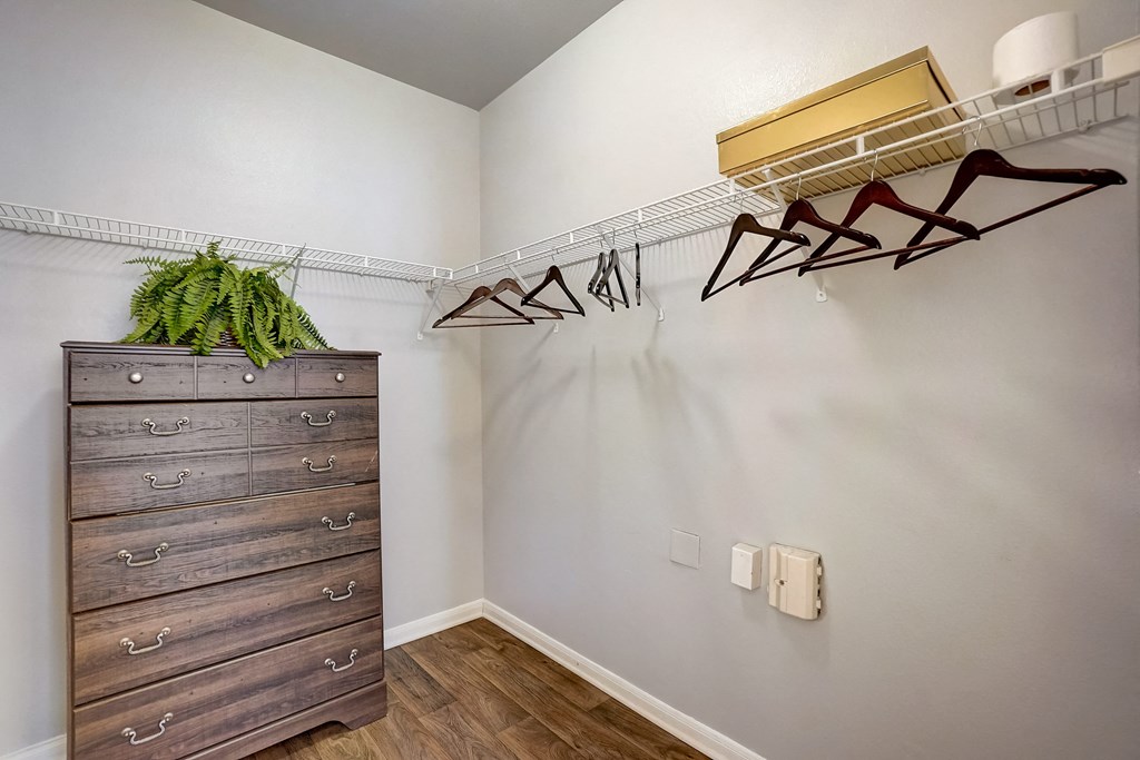 a closet with a dresser and shoe racks on the wall