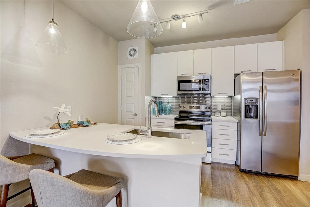 a kitchen with a white counter top and a stainless steel refrigerator