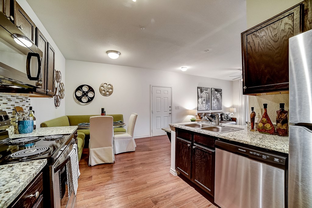 a kitchen and living room with white walls and wood flooring