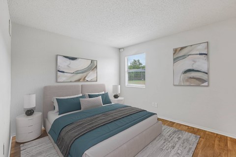 A bedroom with a large bed and two paintings on the wall.