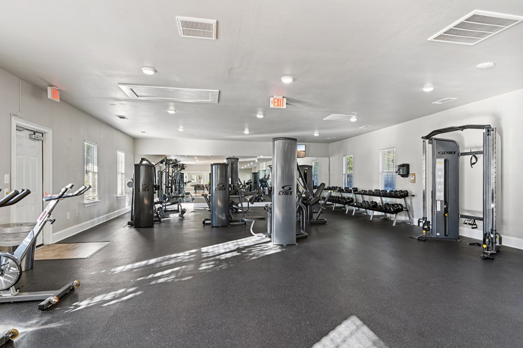 A gym with a variety of equipment including treadmills, weights, and exercise machines.