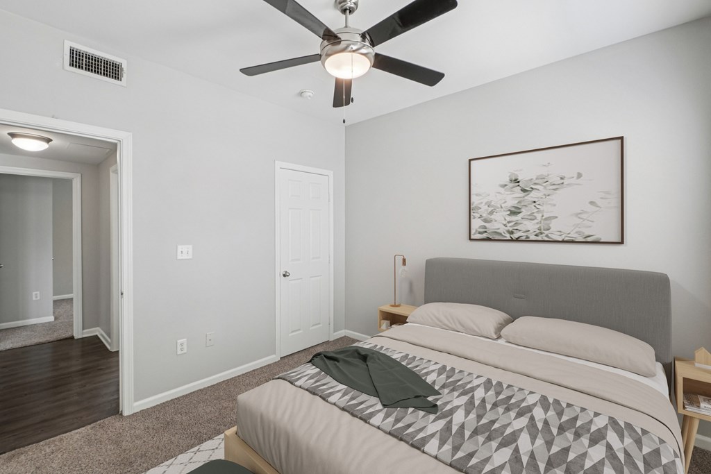 A bedroom with a bed, a ceiling fan, and a painting on the wall.
