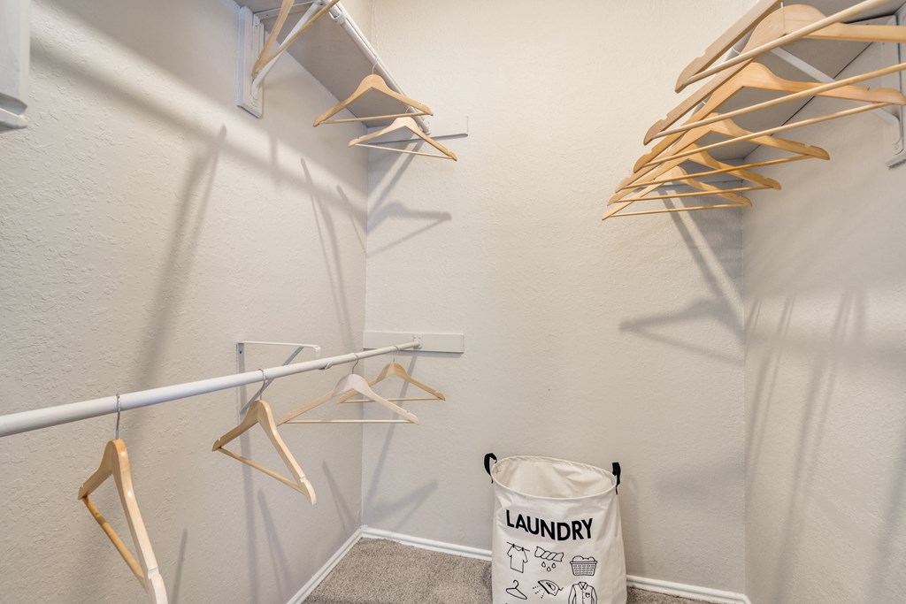 a walk in closet with clothes racks and a laundry basket