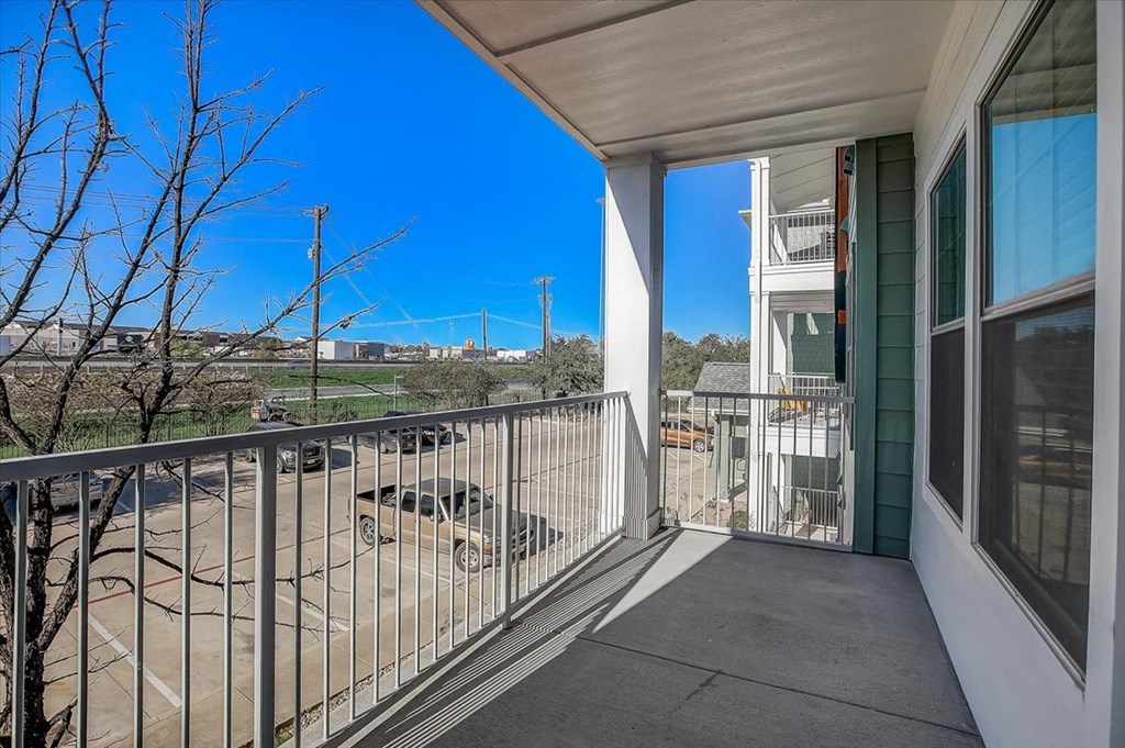 the view from the balcony of a home with a car parked on the street
