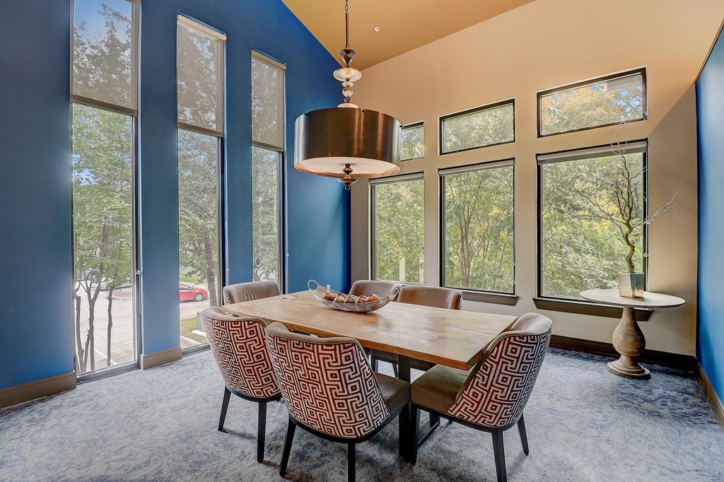 a dining room with a table and chairs and large windows