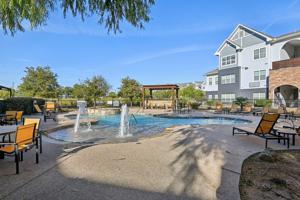 A pool area with a waterfall and lounge chairs.
