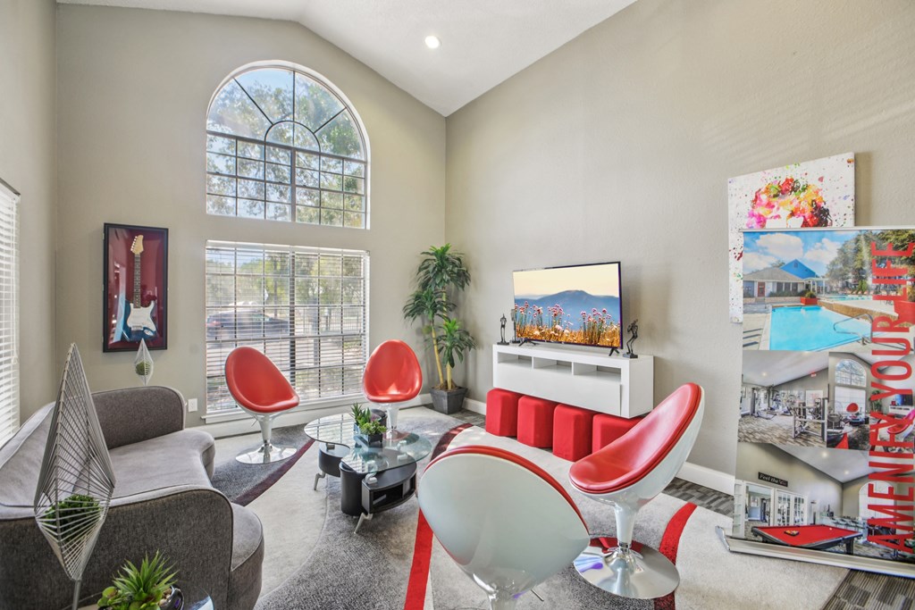 A living room with a grey sofa, red chairs, and a TV.
