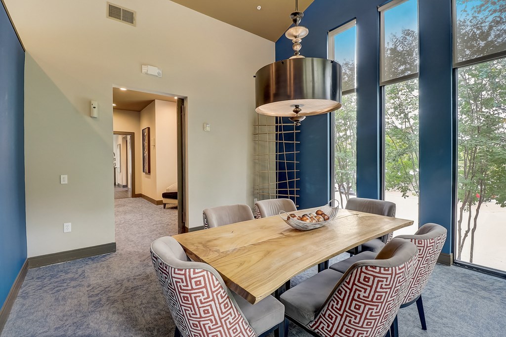 a dining room with a wooden table and chairs and large windows