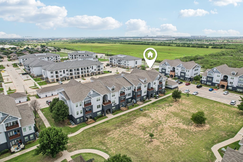 A bird's eye view of a residential area with apartment buildings and a large open field.