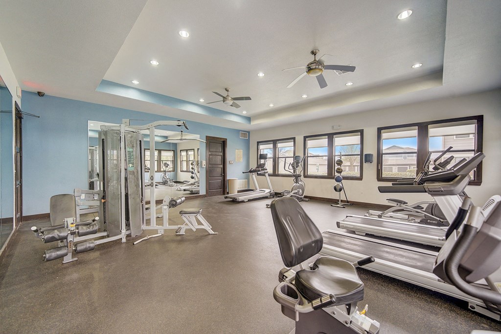 a gym with weights and cardio equipment and windows