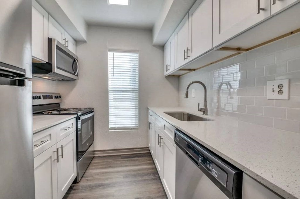 an empty kitchen with white cabinets and a sink