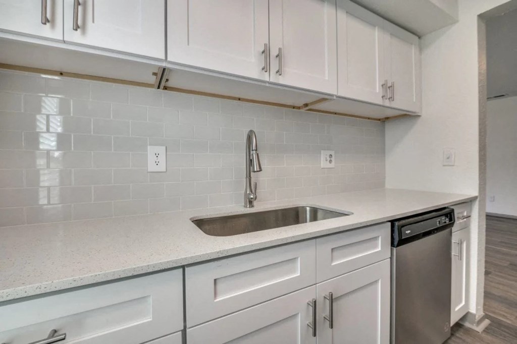 an empty kitchen with white cabinets and a sink