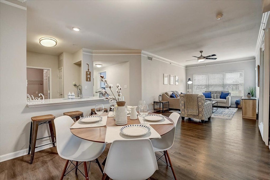 a dining area with a table and chairs and a living room in the background