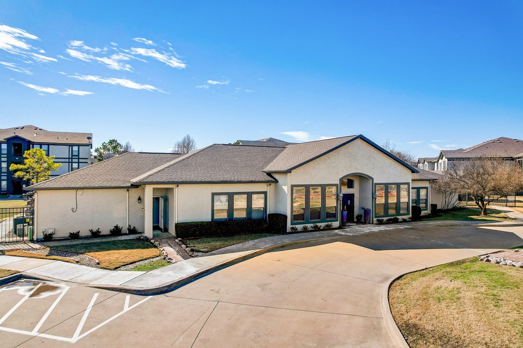 the front of a white house with blue doors and a driveway