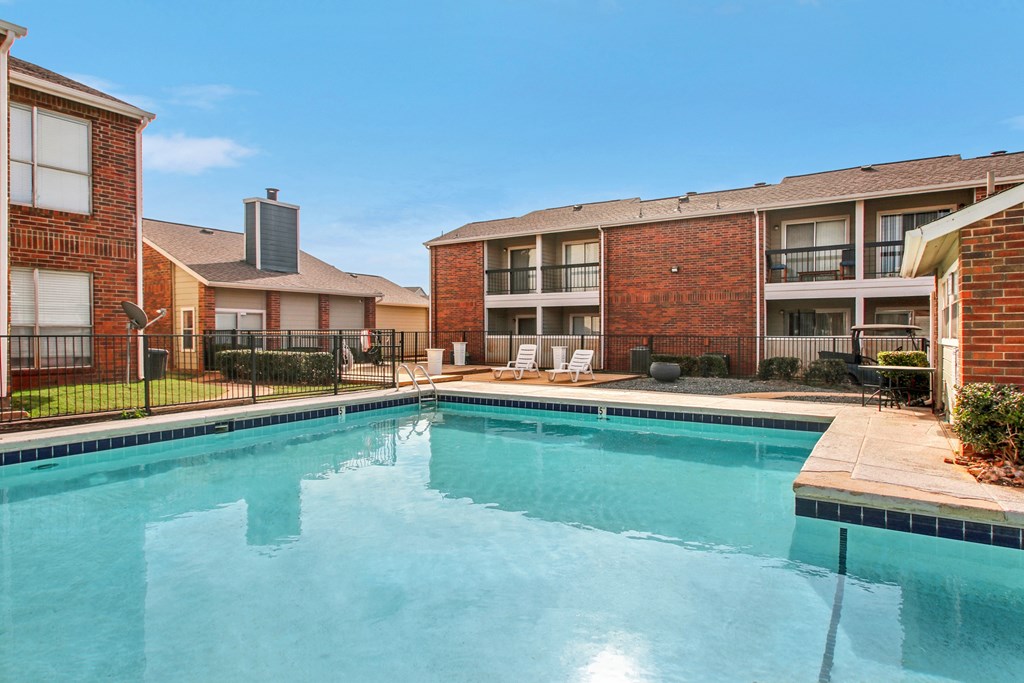 A swimming pool in front of a brick building with a clear blue sky.