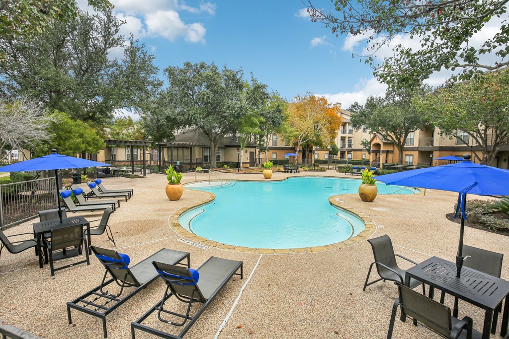 A pool surrounded by chairs and umbrellas in a sunny day.