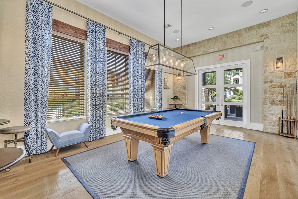 a pool table in a living room with windows