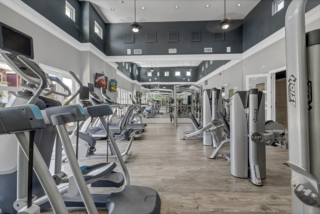 a gym with cardio equipment and weights on a wood floor