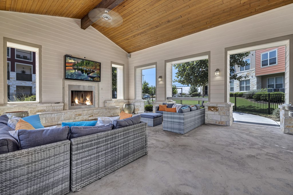 a covered patio with couches and a fireplace