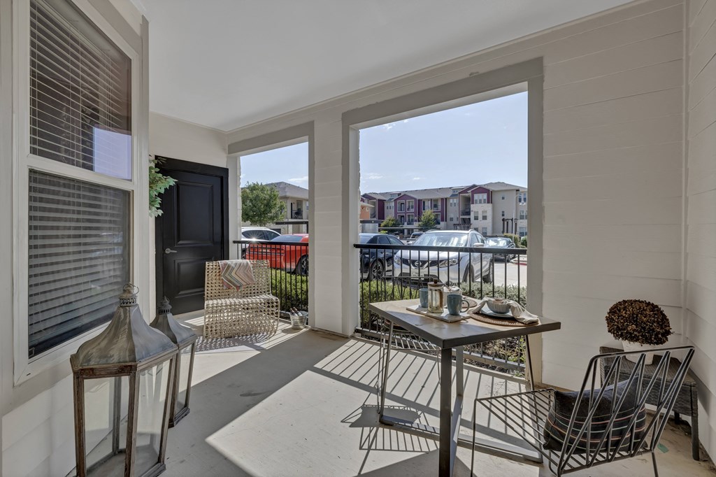 a porch with a table and chairs and a view of a parking lot
