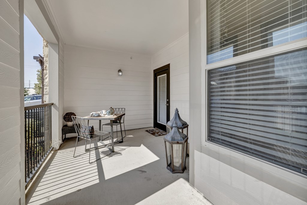a covered porch with a table and chairs and a window