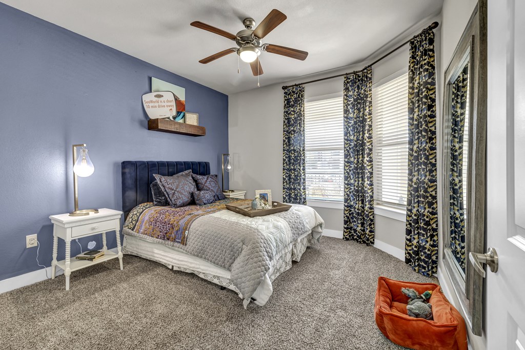 a bedroom with blue walls and a bed and a ceiling fan