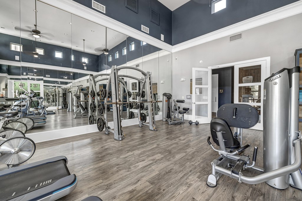 a gym with cardio equipment and mirrors on the walls