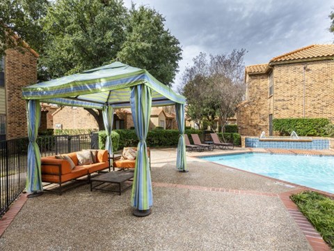 a swimming pool with a gazebo and chairs next to it