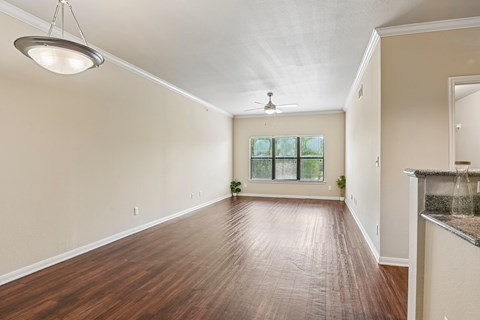 A spacious room with wooden floors and a ceiling fan.