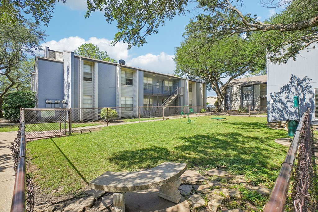 A modern building with a fence and a green lawn in front.