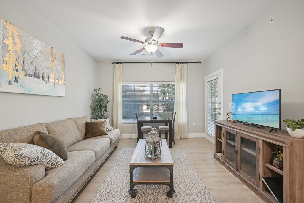A living room with a couch, a coffee table, a television, and a painting on the wall.