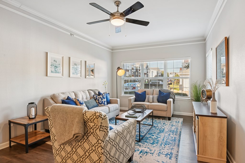 A living room with a couch, chair, and a fan.