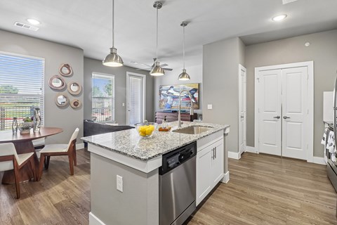 A kitchen with a large island and a dining table with chairs.