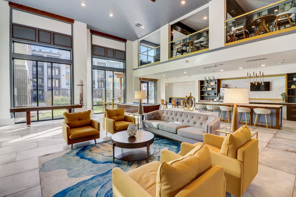 a living room with couches and chairs and a kitchen with large windows