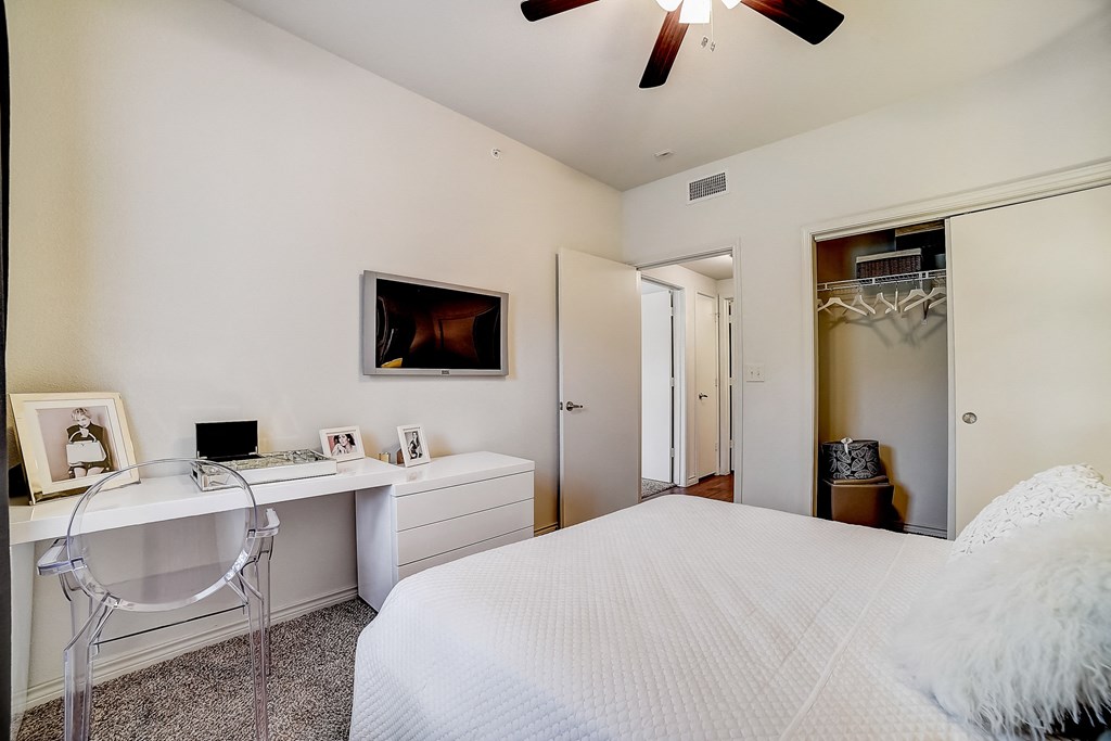 a bedroom with a large white bed and a white desk with a white chair