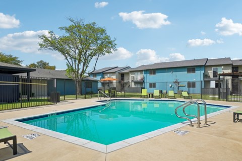 A swimming pool in a sunny day surrounded by a fence.