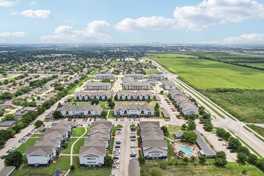 A bird's eye view of a residential area with multiple houses and a swimming pool.