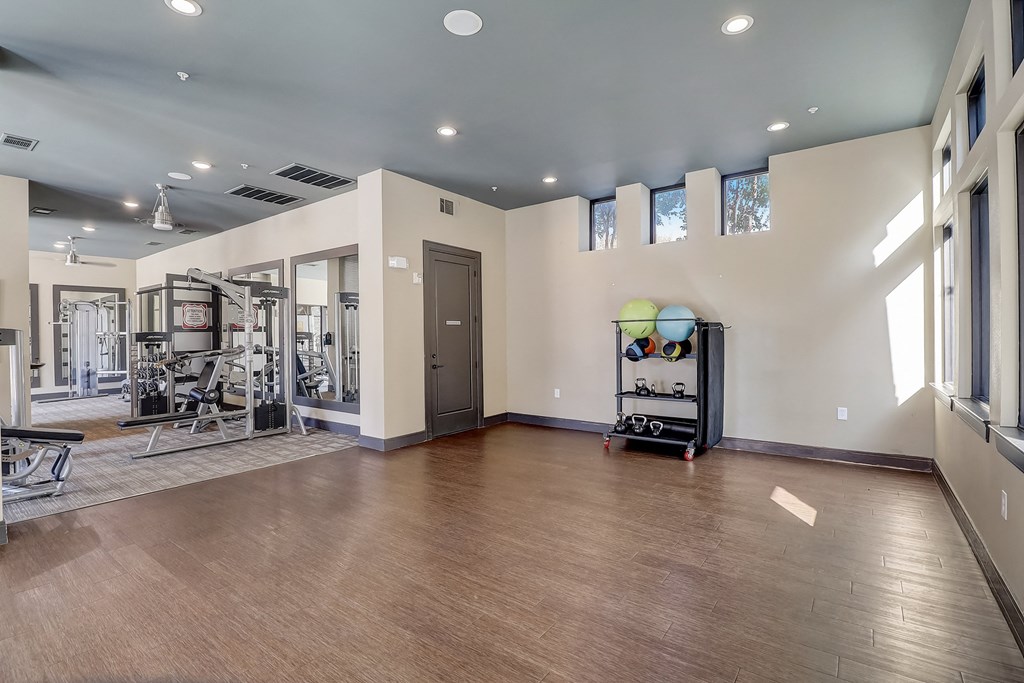 a workout room with a treadmill and weights on a wooden floor