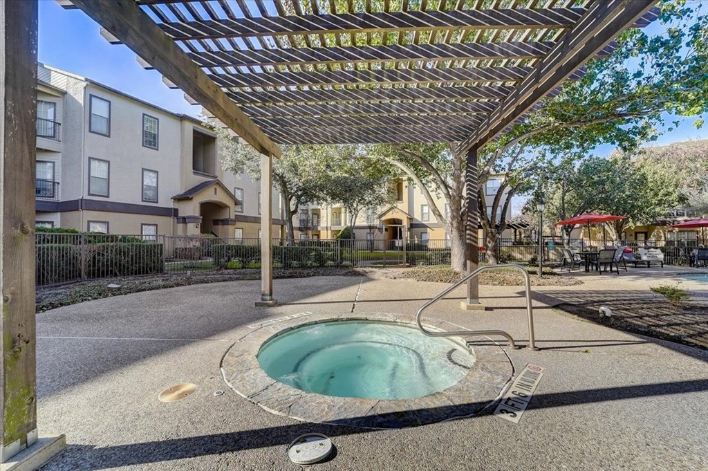 a hot tub in a courtyard with a pergola and apartment buildings
