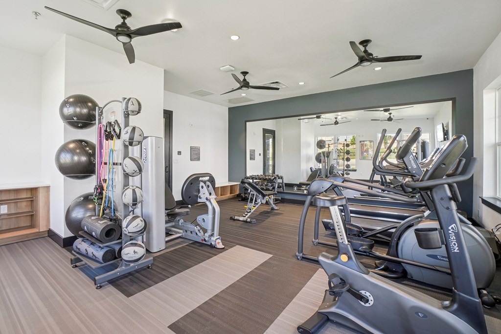 A spacious gym with a variety of equipment including treadmills, elliptical machines, and weights.
