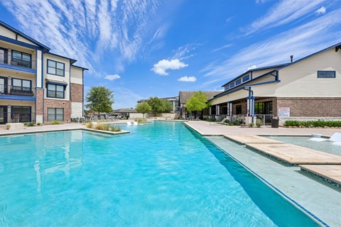 A large swimming pool in front of a building with a blue sky above.