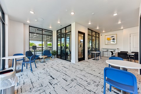 A white table with blue chairs is in a room with a brick floor.