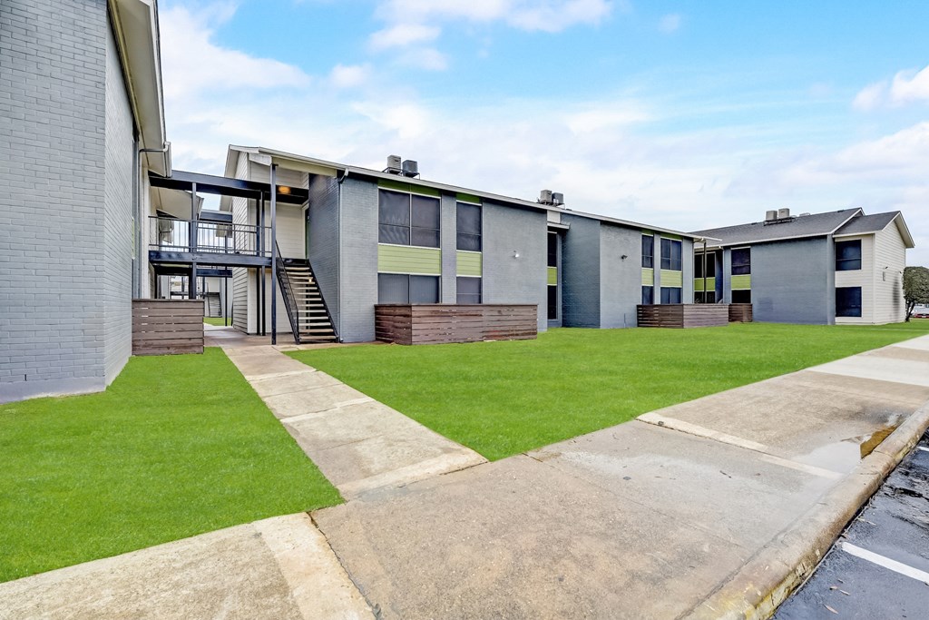 a row of houses with a green lawn and a blue sky in the background